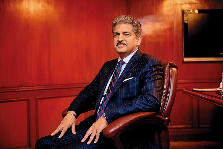 Anand Mahindra seated in his office, dressed in a navy pinstriped suit.