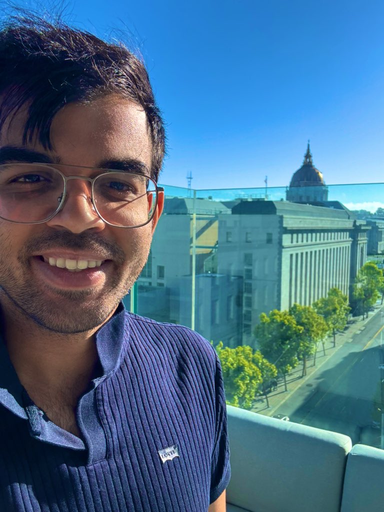 Sudarshan Kamath, founder of Smallest AI, standing on a balcony with city buildings in the background.
