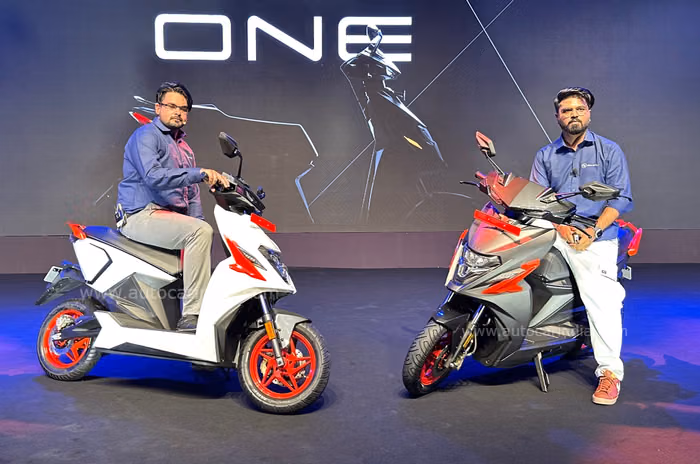 Two Simple Energy executives sitting on Simple One electric scooters during a product launch event.