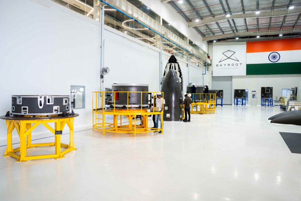 Skyroot Aerospace’s cleanroom facility in Hyderabad displaying rocket modules and payload fairings under assembly, with the Indian flag and company logo visible in the background.