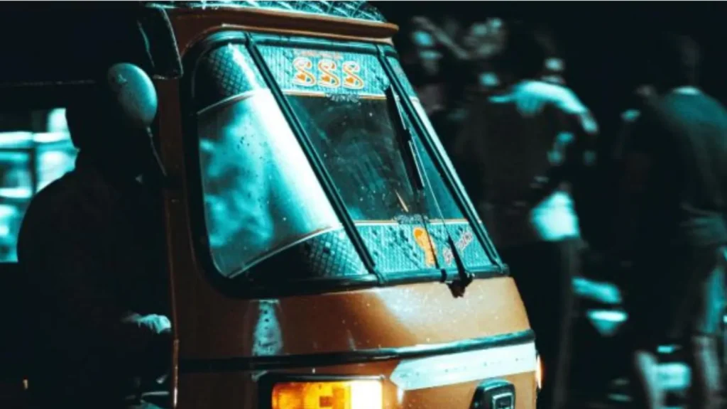 A yellow autorickshaw parked on a dimly lit street at night.