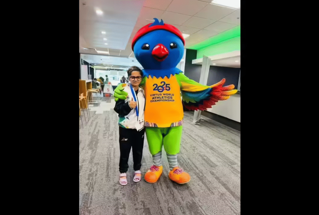 Tarunika Ghosh standing beside the colorful Virtus Championship mascot after her record-breaking performance in Brisbane.