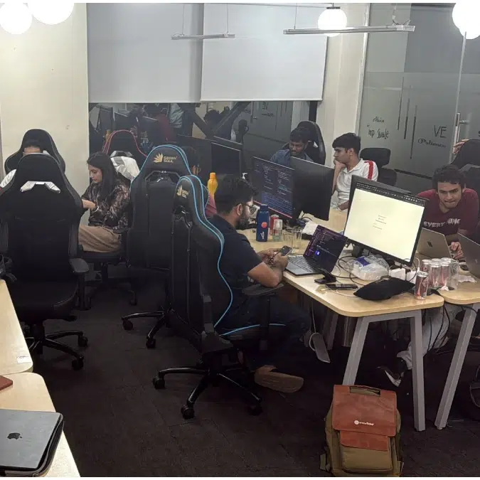 Employees working late at night inside a modern office with multiple computer desks.