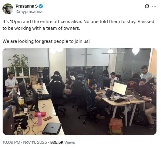 Employees working late at night inside a brightly lit office space with computers and desks.